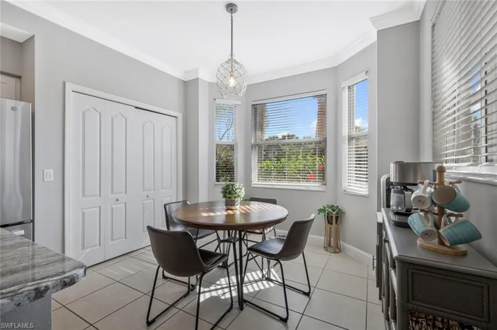 Dining area featuring crown molding, light tile patterned flooring, and suspended lighting