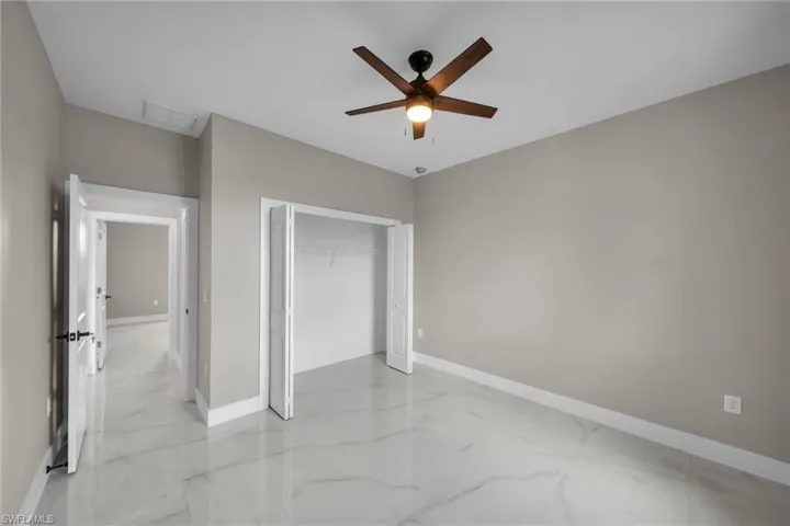 Unfurnished bedroom with a closet, ceiling fan, and light marble finish flooring