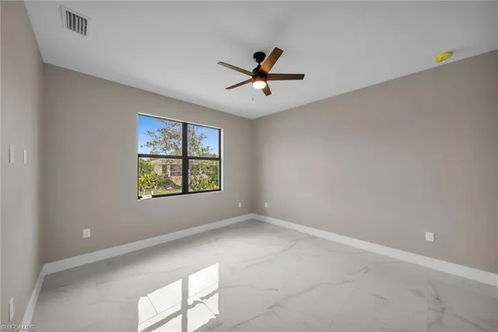 Empty room with light marble finish floors and a ceiling fan