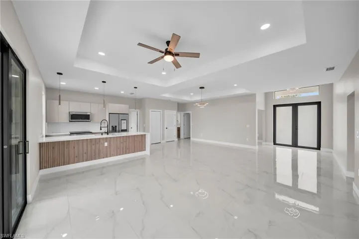 Unfurnished living room featuring french doors, recessed lighting, a ceiling fan, and a raised ceiling