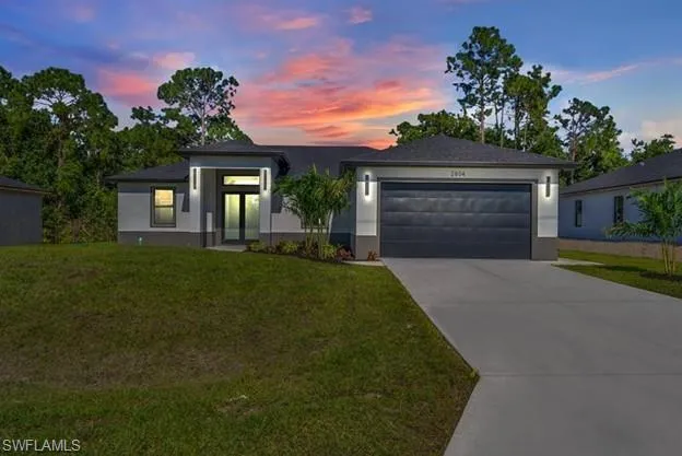 View of front of house featuring a front yard, a garage, concrete driveway, and stucco siding
