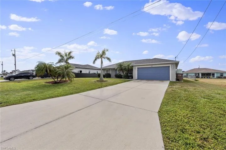 Ranch-style home with concrete driveway, a front lawn, an attached garage, and stucco siding