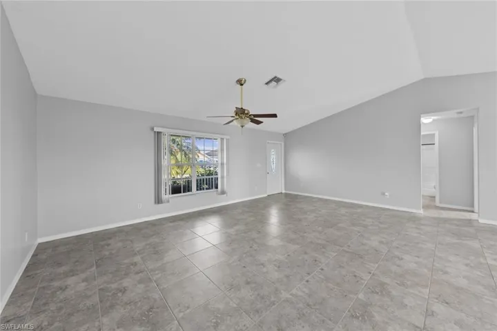 Unfurnished living room featuring vaulted ceiling, ceiling fan, and baseboards