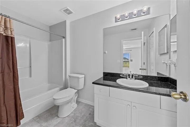 Full bath with toilet, vanity, tile patterned flooring, and shower / tub combo