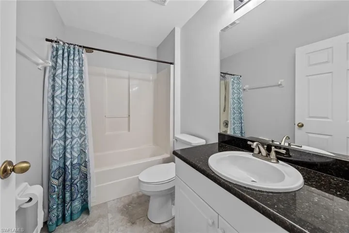 Full bathroom featuring toilet, vanity, shower / bath combo with shower curtain, and tile patterned flooring