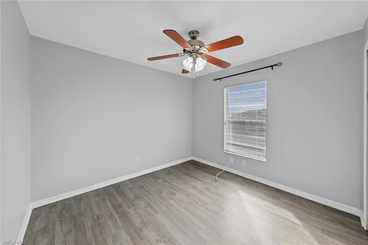 Empty room with wood finished floors, ceiling fan, and baseboards
