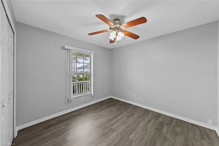 Unfurnished bedroom with a closet, wood finished floors, baseboards, and ceiling fan