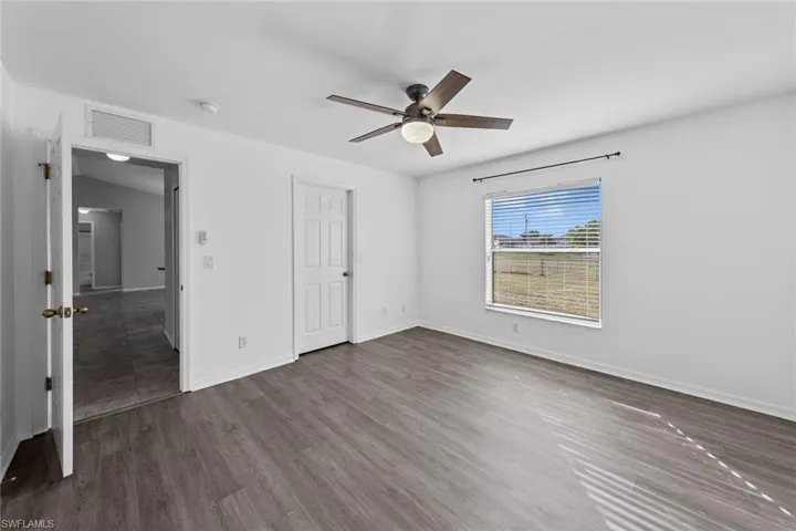 Unfurnished bedroom featuring baseboards, dark wood-style flooring, and a ceiling fan