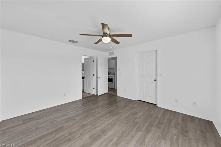 Unfurnished bedroom with wood finished floors, baseboards, washer / dryer, and ceiling fan