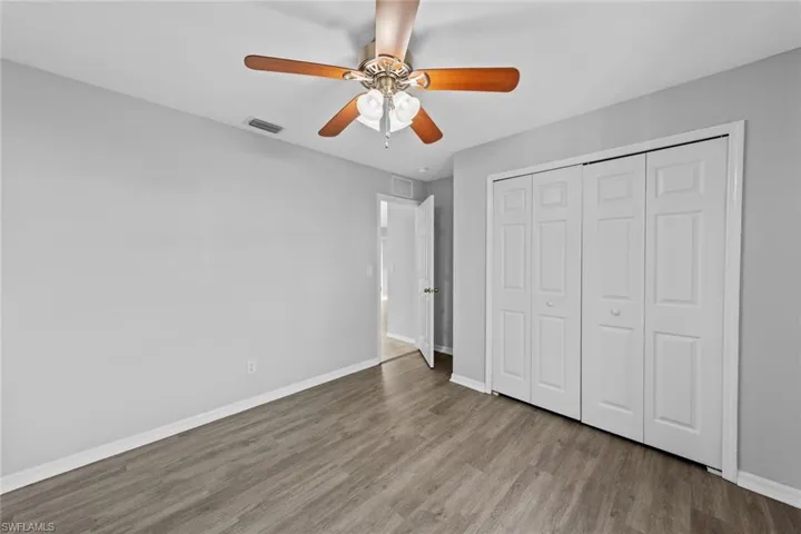 Unfurnished bedroom with wood finished floors, baseboards, a closet, and a ceiling fan