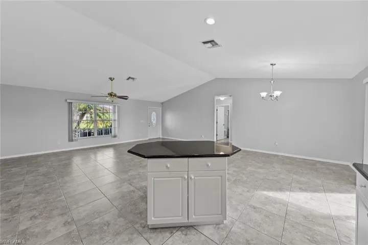 Kitchen featuring vaulted ceiling, open floor plan, a chandelier, ceiling fan, and a kitchen island