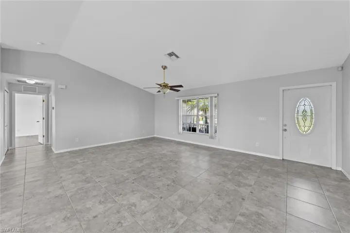 Unfurnished living room with lofted ceiling, ceiling fan, tile patterned floors, and baseboards