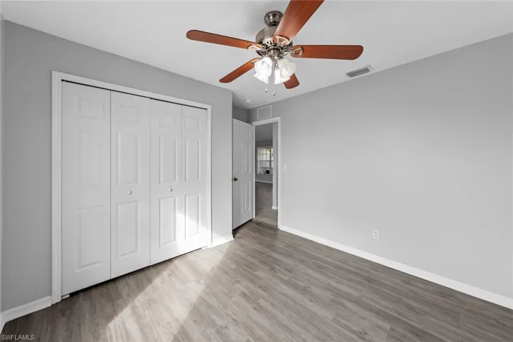 Unfurnished bedroom featuring wood finished floors, baseboards, a closet, and a ceiling fan