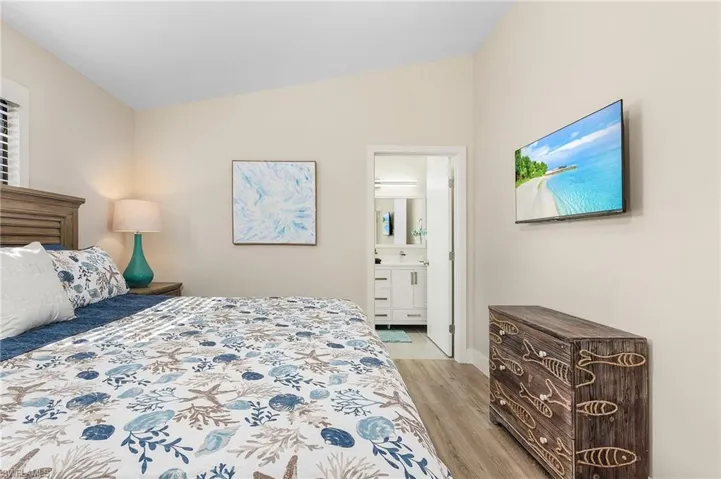 Bedroom featuring lofted ceiling, light wood-style flooring, and ensuite bathroom