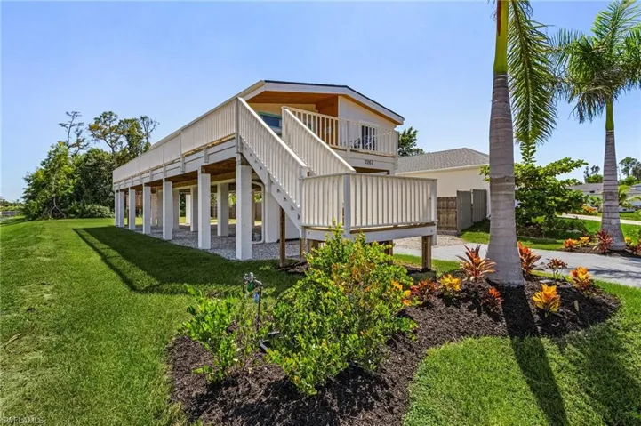 Rear view of house with a lawn, a wooden deck, stairs, and fence