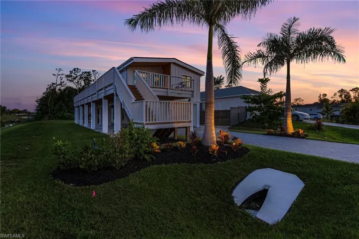 View of front of house with stairs, a front lawn, and fence
