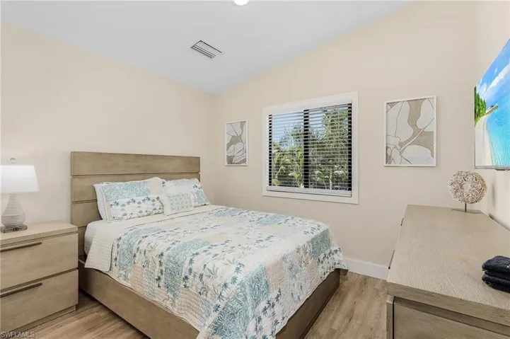 Bedroom featuring vaulted ceiling, light wood-style flooring, baseboards, and visible vents