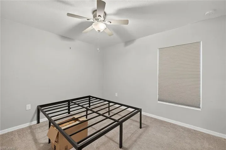 Bedroom with light carpet, ceiling fan, and a textured ceiling