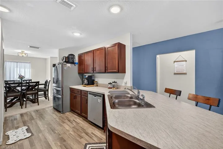 Kitchen with light countertops, light wood-type flooring, appliances with stainless steel finishes, a peninsula, and a breakfast bar area