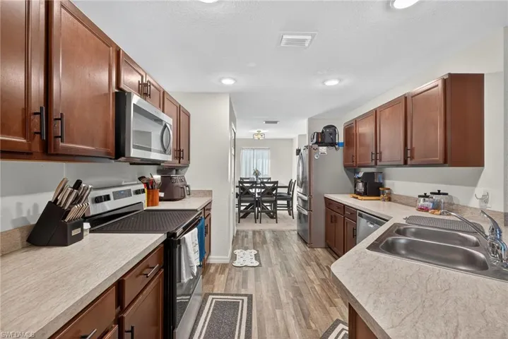 Kitchen featuring stainless steel appliances, light wood-type flooring, light countertops, brown cabinetry, and a textured ceiling