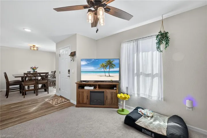 Carpeted living area with ceiling fan and wood finished floors