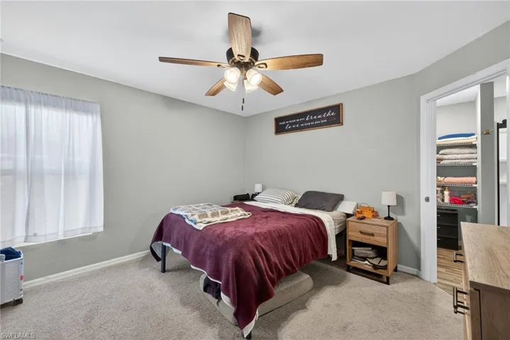 Bedroom with a spacious closet, ceiling fan, and light colored carpet
