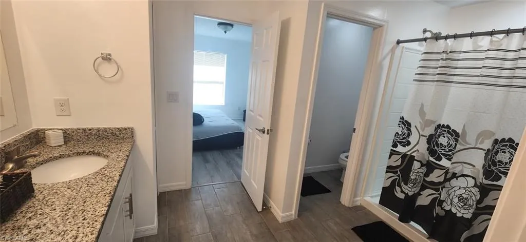 Bathroom with vanity, a shower stall, dark wood-style floors, and ensuite bath