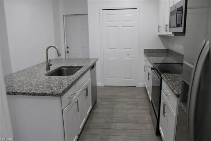Kitchen featuring stainless steel appliances, white cabinets, and dark stone counters