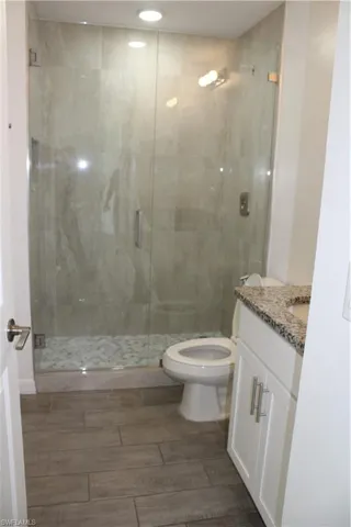 Bathroom with vanity, a stall shower, recessed lighting, and wood finish floors
