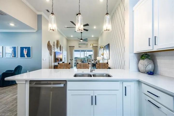 Kitchen with stainless steel dishwasher, kitchen peninsula, and white cabinets