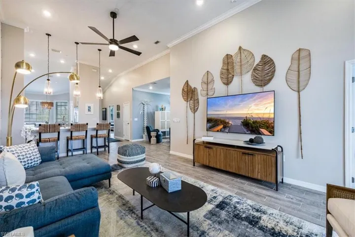 Living room with light hardwood / wood-style flooring, ornamental molding, and ceiling fan