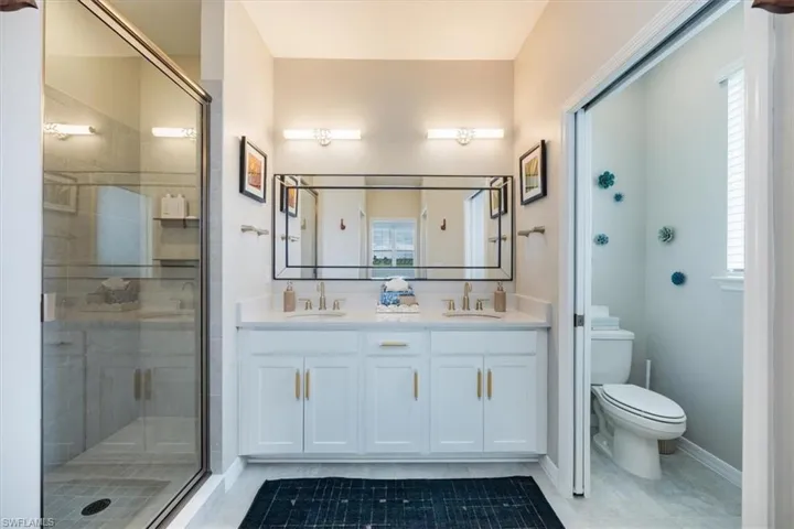 Bathroom with an enclosed shower, vanity, tile patterned floors, and toilet