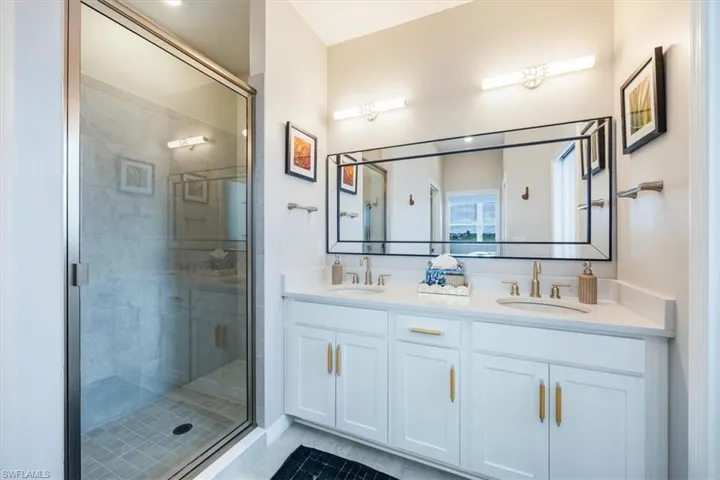 Bathroom featuring walk in shower, vanity, and tile patterned flooring