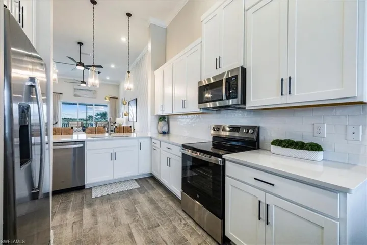 Kitchen featuring sink, white cabinetry, hanging light fixtures, appliances with stainless steel finishes, and kitchen peninsula