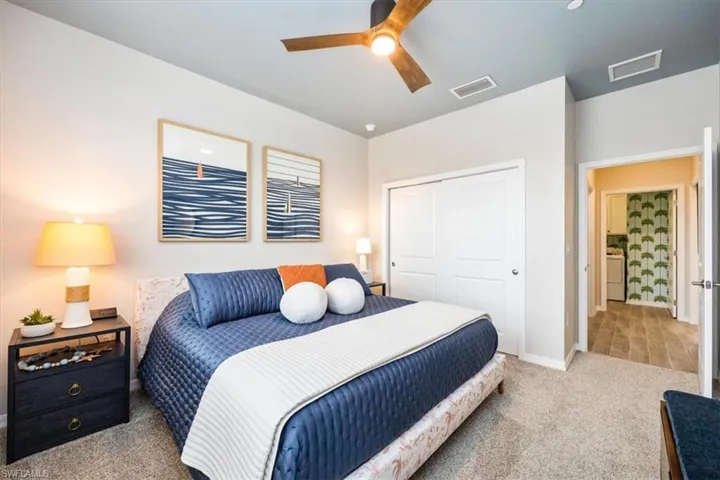 Bedroom featuring ceiling fan, washer / clothes dryer, a closet, and light carpet