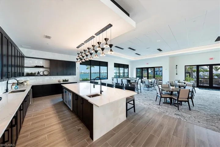 Kitchen with pendant lighting, a kitchen island with sink, sink, and french doors