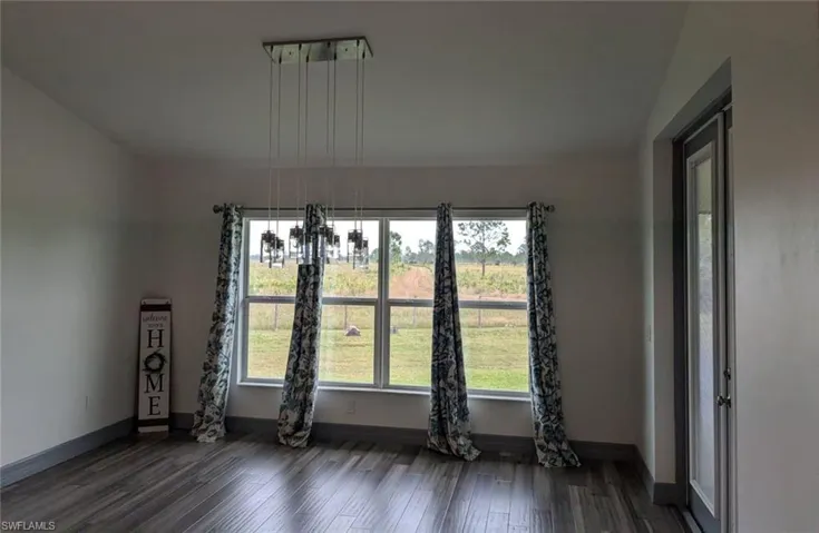 Spare room with dark wood-type flooring, a chandelier, and vaulted ceiling