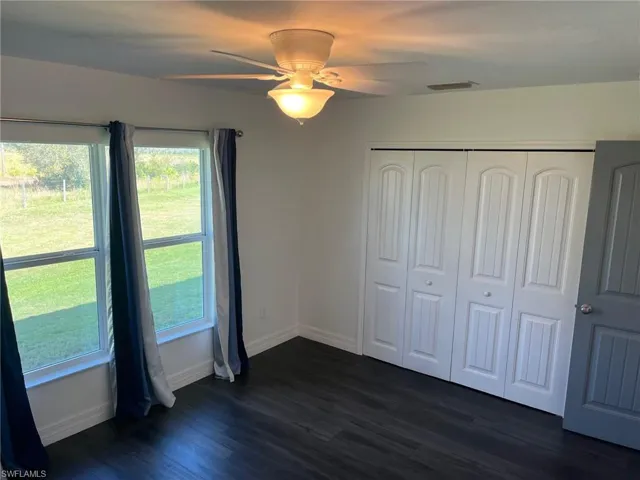 Unfurnished bedroom featuring dark hardwood / wood-style flooring, ceiling fan, and a closet