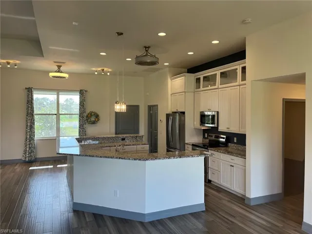 Kitchen featuring white cabinets, stainless steel appliances, hanging light fixtures, and a center island