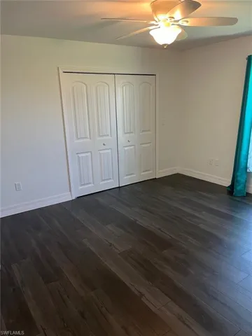 Unfurnished bedroom featuring dark hardwood / wood-style flooring, ceiling fan, and a closet