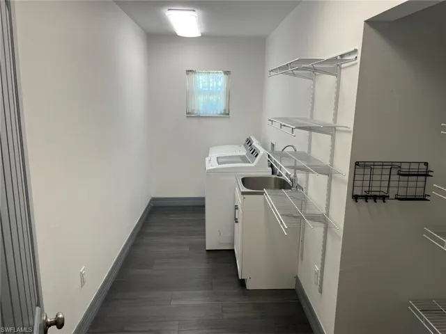 Clothes washing area with washer and clothes dryer and dark hardwood / wood-style floors