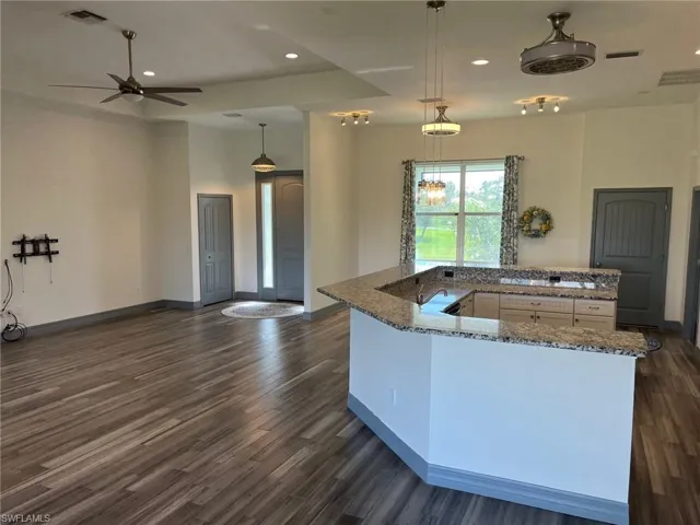 Kitchen with stone countertops, dark hardwood / wood-style floors, white cabinetry, and pendant lighting
