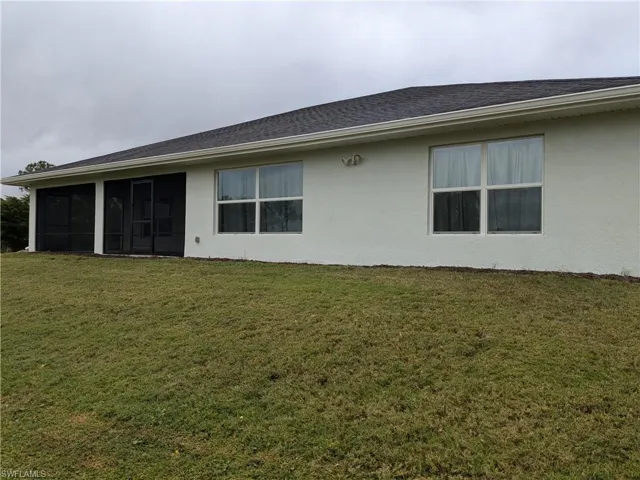 Rear view of property featuring a lawn and a sunroom