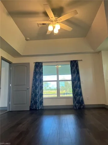 Empty room with dark wood-type flooring and ceiling fan