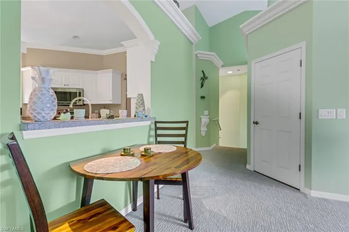 Dining space featuring light carpet, arched walkways, and ornamental molding