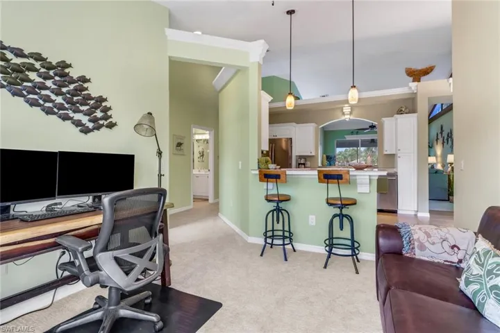 Office area featuring light carpet, ornamental molding, and high vaulted ceiling