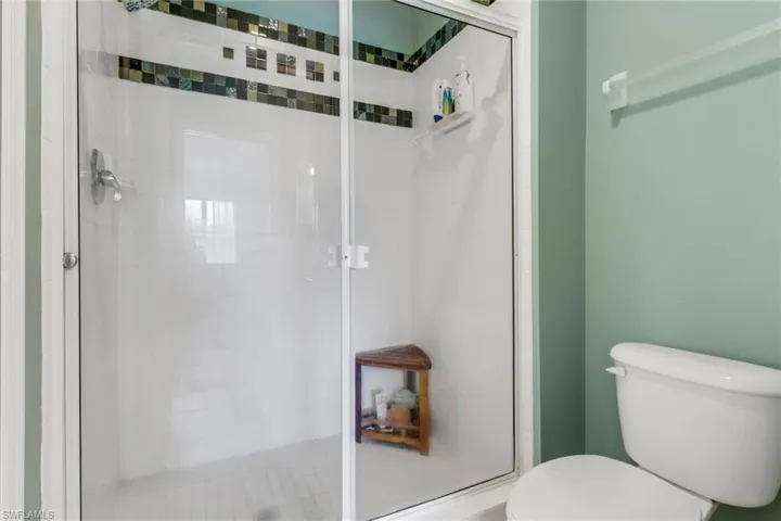 Full bath featuring a shower stall and toilet