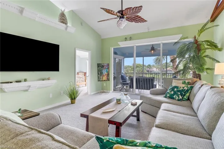 Carpeted living area with high vaulted ceiling and ceiling fan