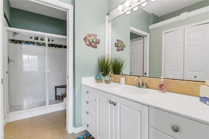 Bathroom featuring a stall shower, vanity, and tile patterned flooring