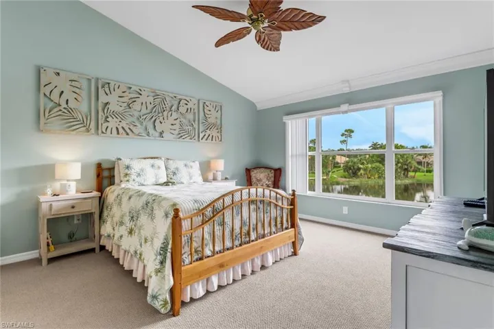 Carpeted bedroom featuring vaulted ceiling, a water view, and ceiling fan
